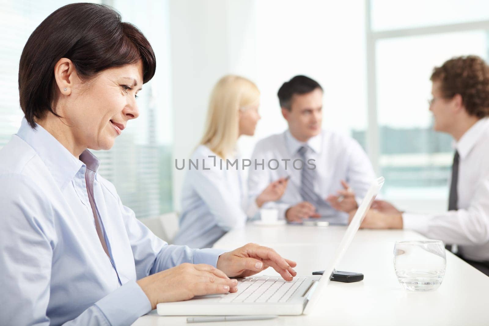 Mature businesswoman sitting in office and typing in working environment