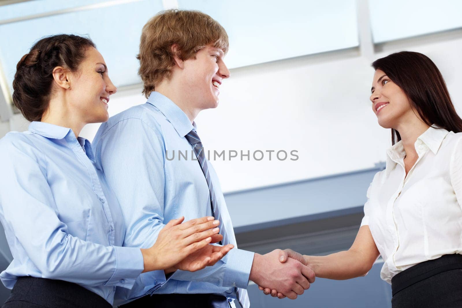 Image of business partners making an agreement with woman clapping her hands near by