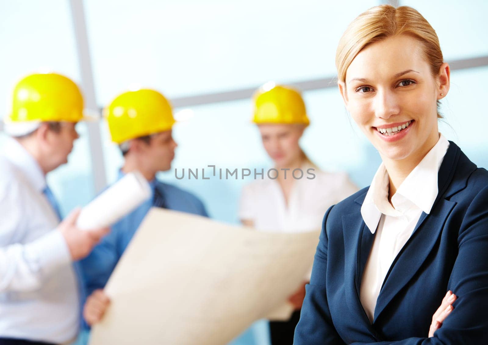 Portrait of beautiful architect folding arms on the background of workers