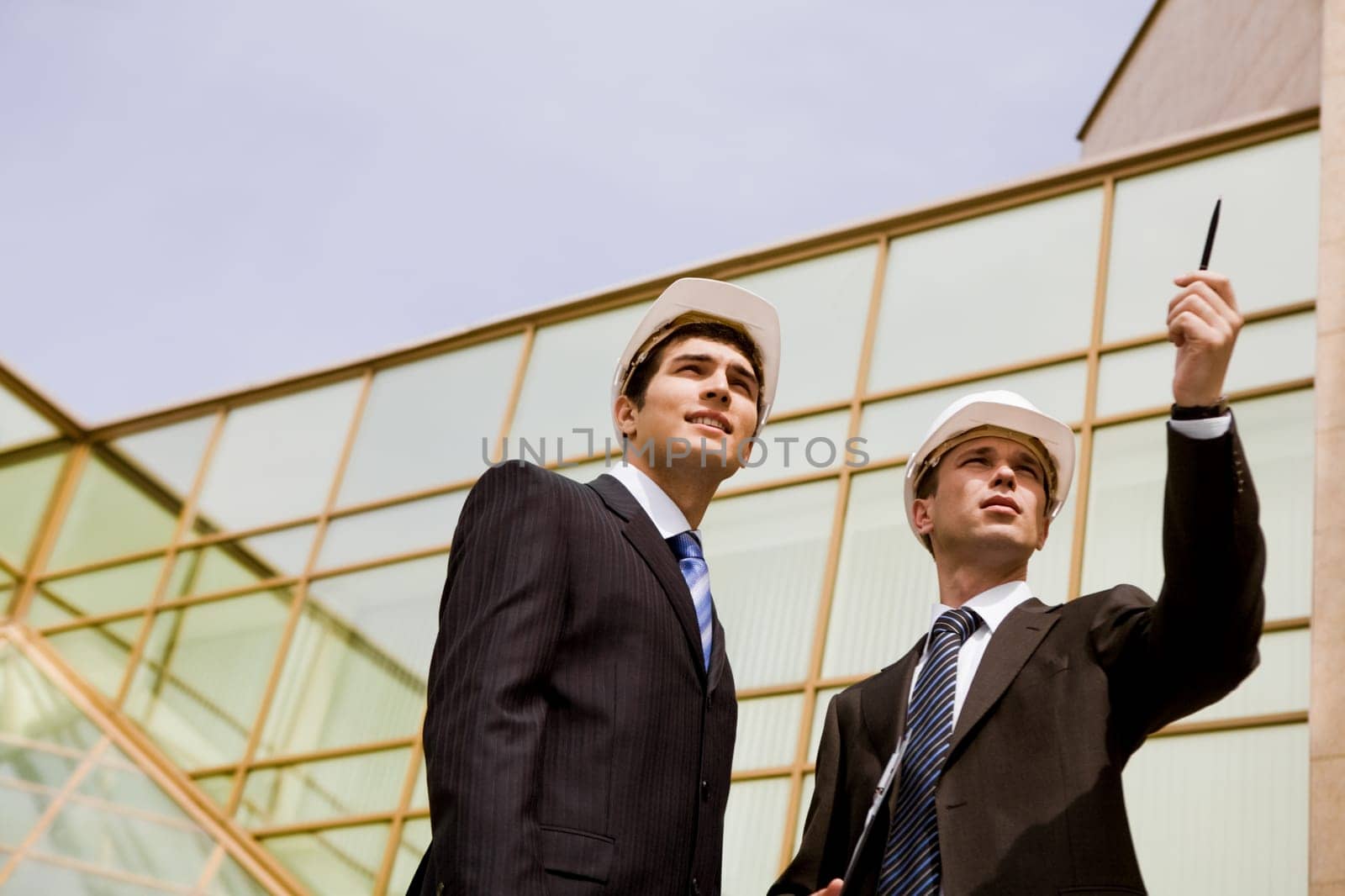 Photo of serious employee pointing at something with confident foreman standing near by