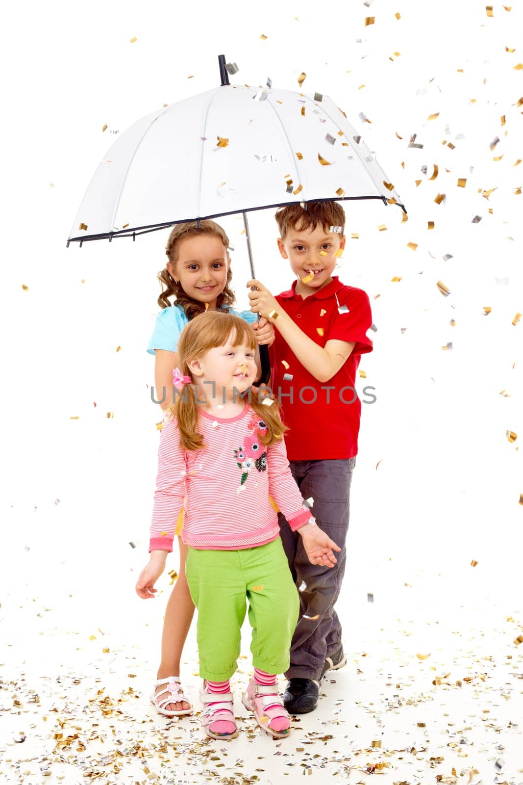 Portrait of smart children under umbrella over confetti falling