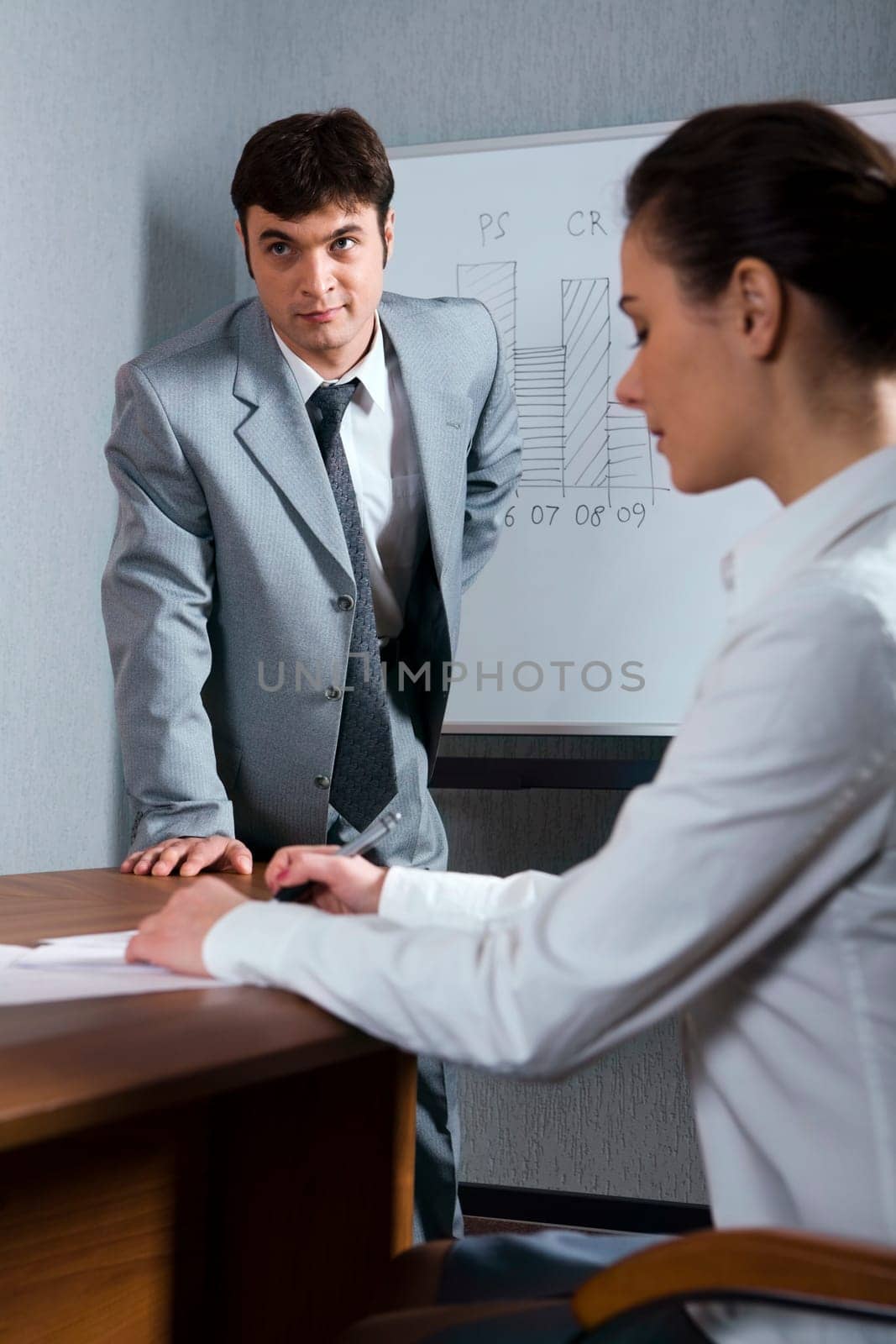 Businessman in the gray suit near the blackboard and writing woman
