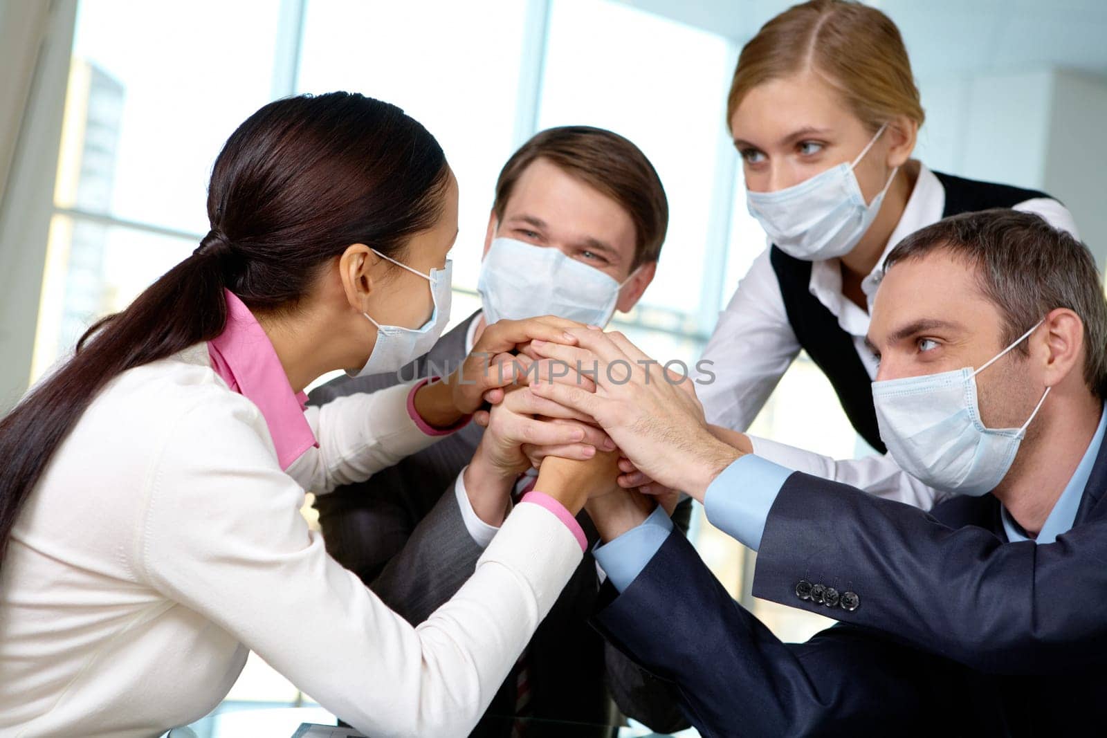 Portrait of business team in protective masks making pile of hands