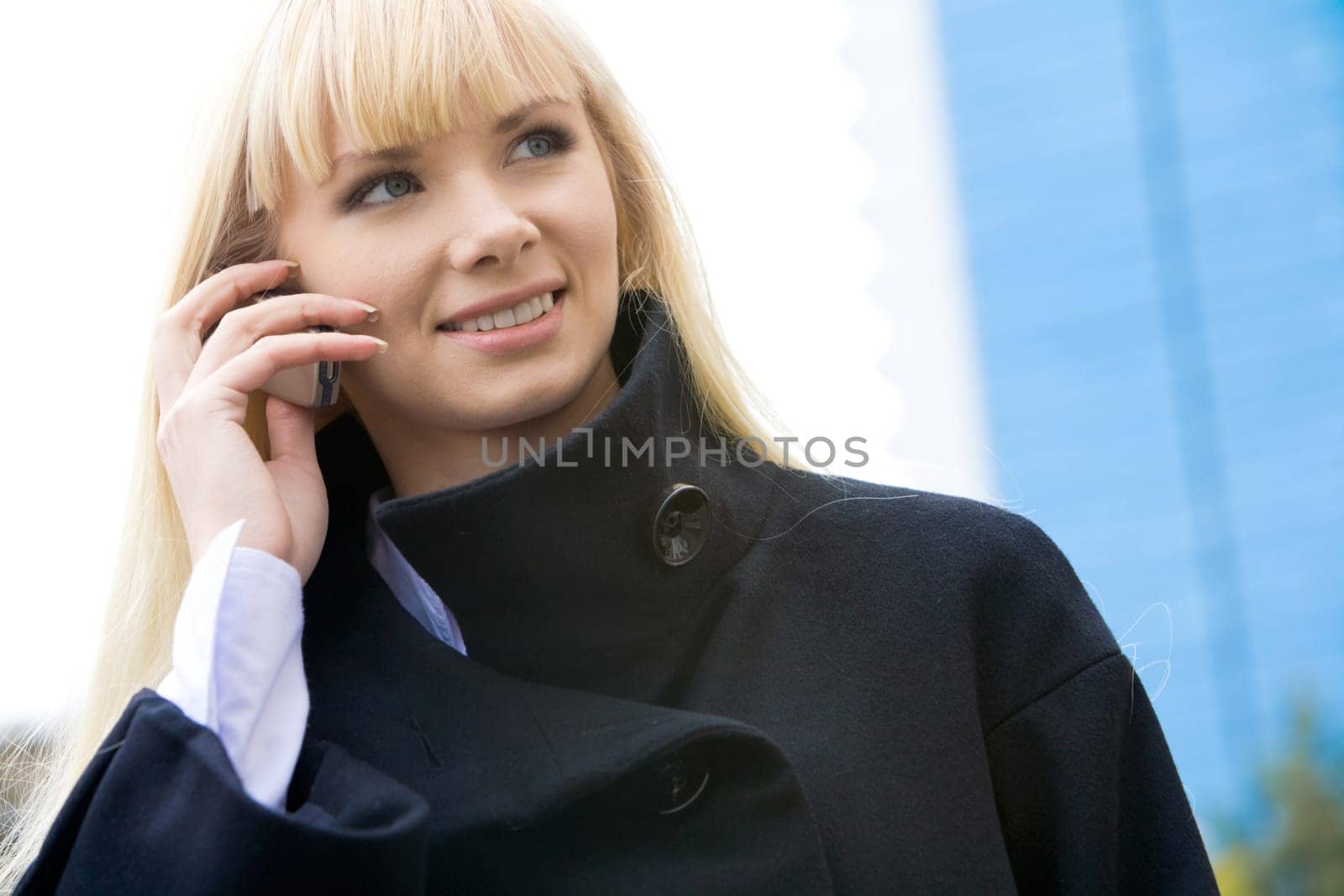 Portrait of elegant woman in black coat phoning outside