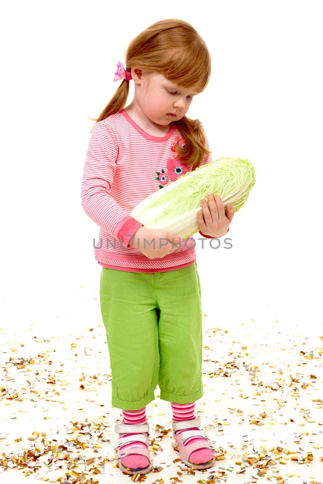 Portrait of serious girl holding Chinese cabbage and looking at it