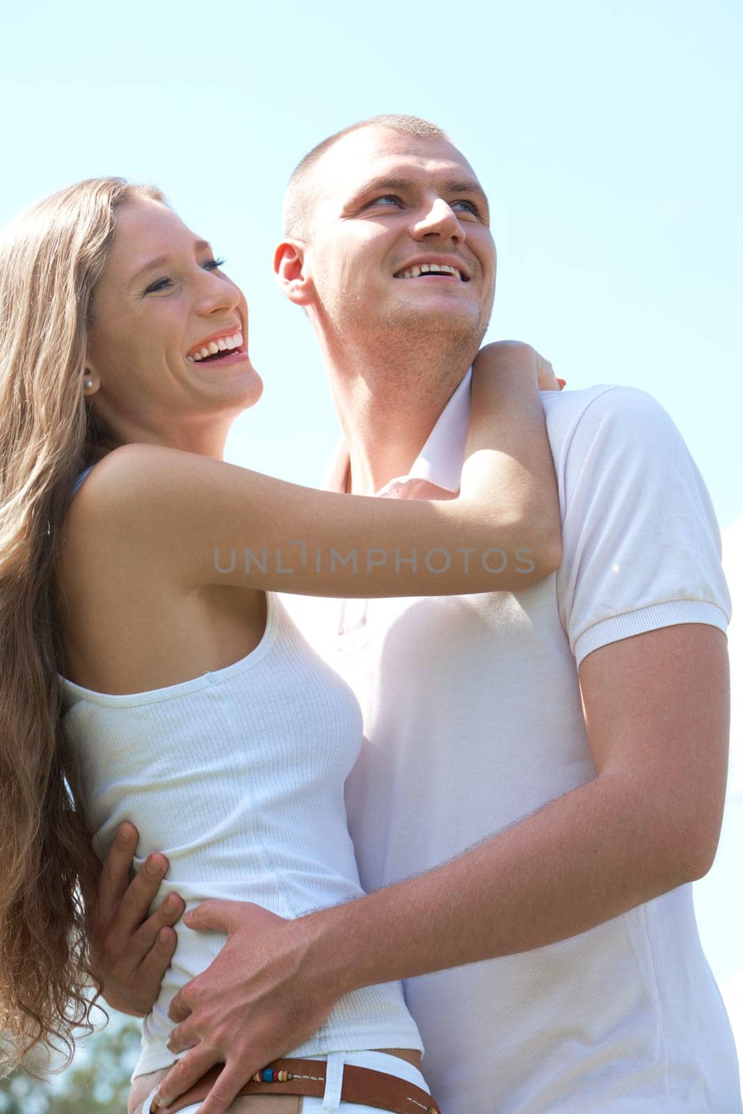 Portrait of happy couple laughing and looking aside while embracing each other