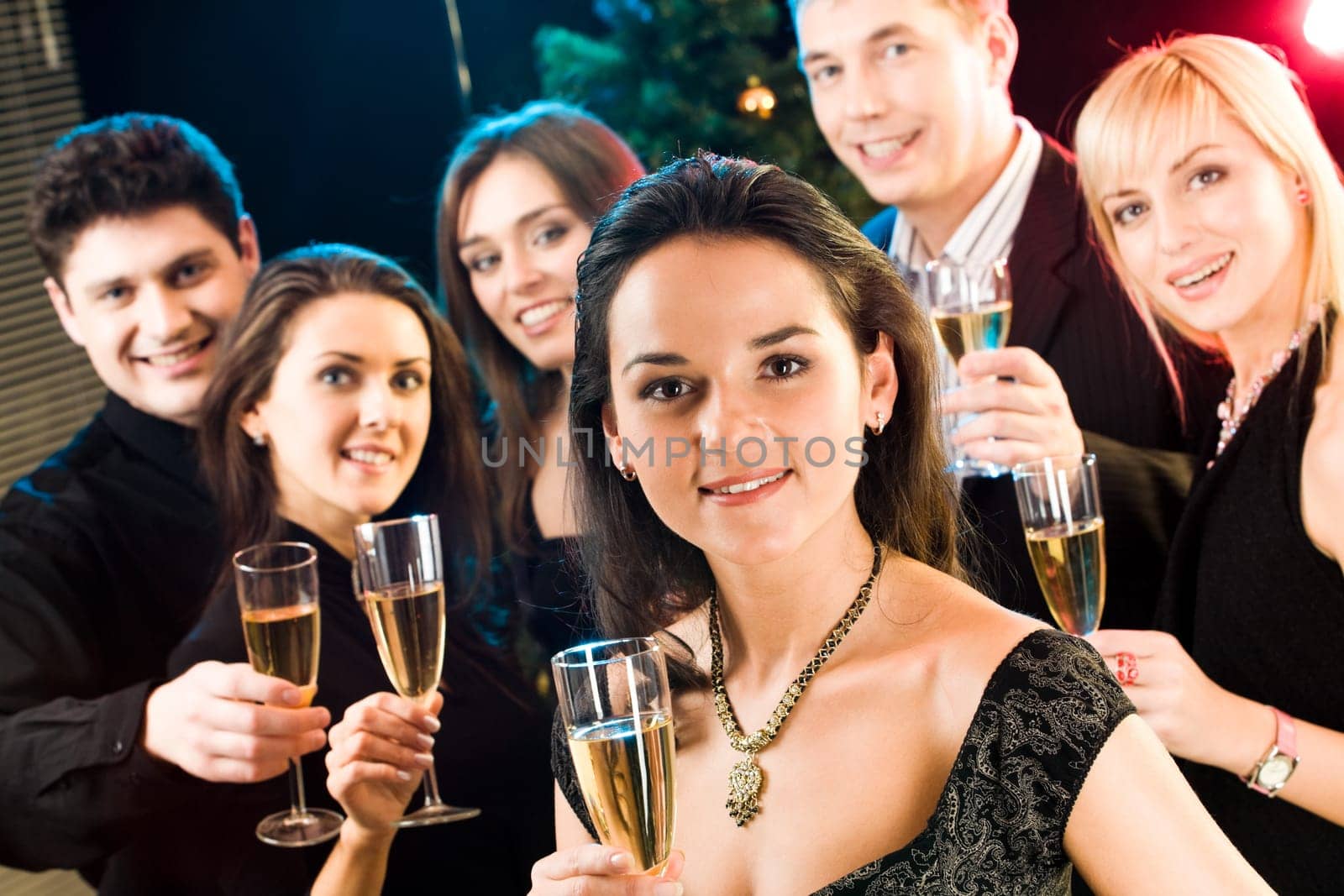 Beautiful woman raising up her glass on the background of five friends