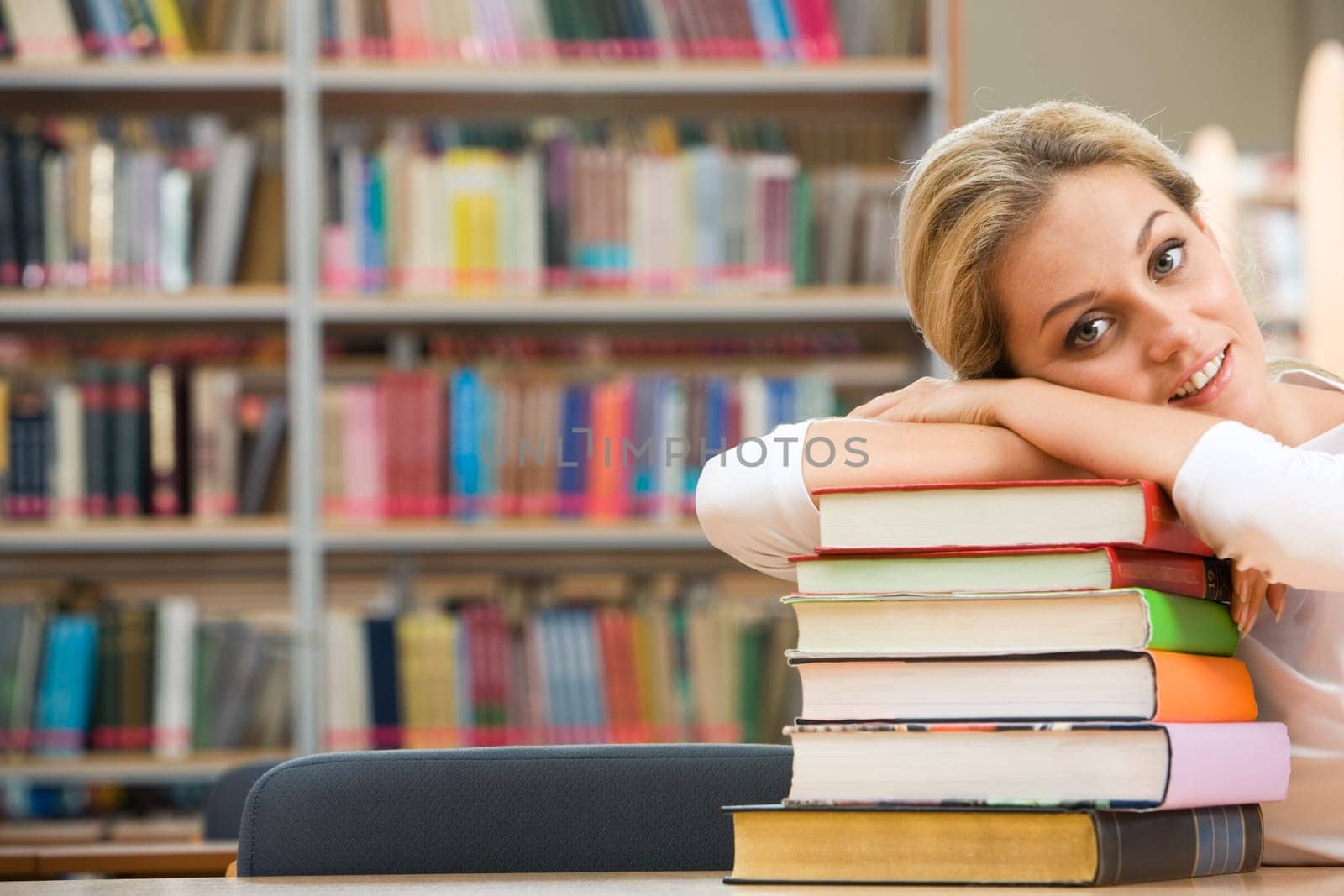 Portrait of tired student lying on the stack of books