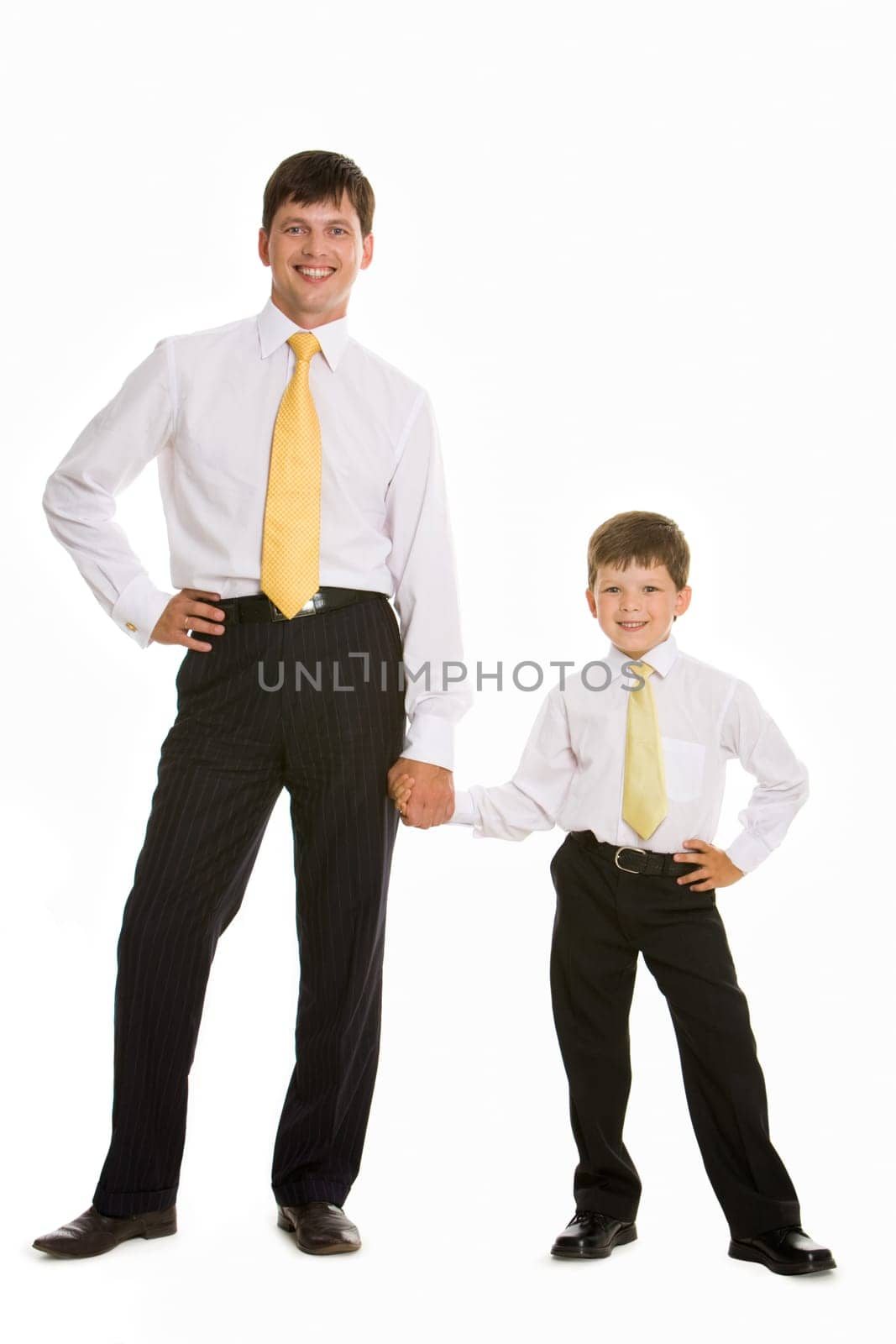 Portrait of smiling man and his son holding by hands over white background