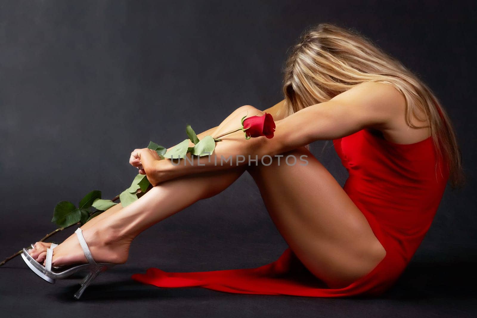 An elegant woman in red dress sitting with a rose