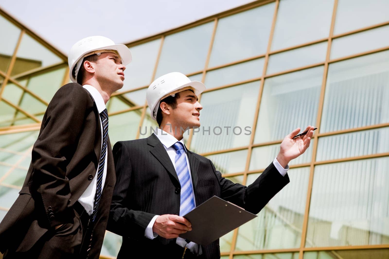 Photo of two co-workers looking at new building while one of them pointing at it