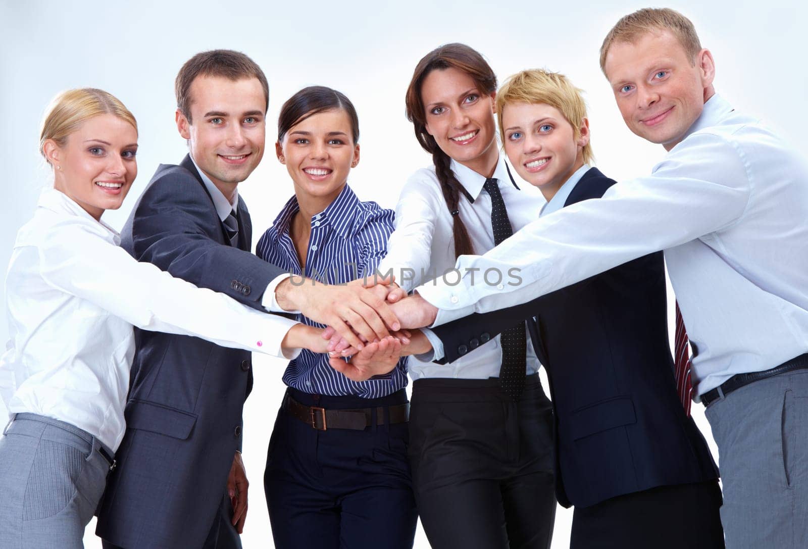 Portrait of friendly business team keeping their hands on top of each other and looking at camera