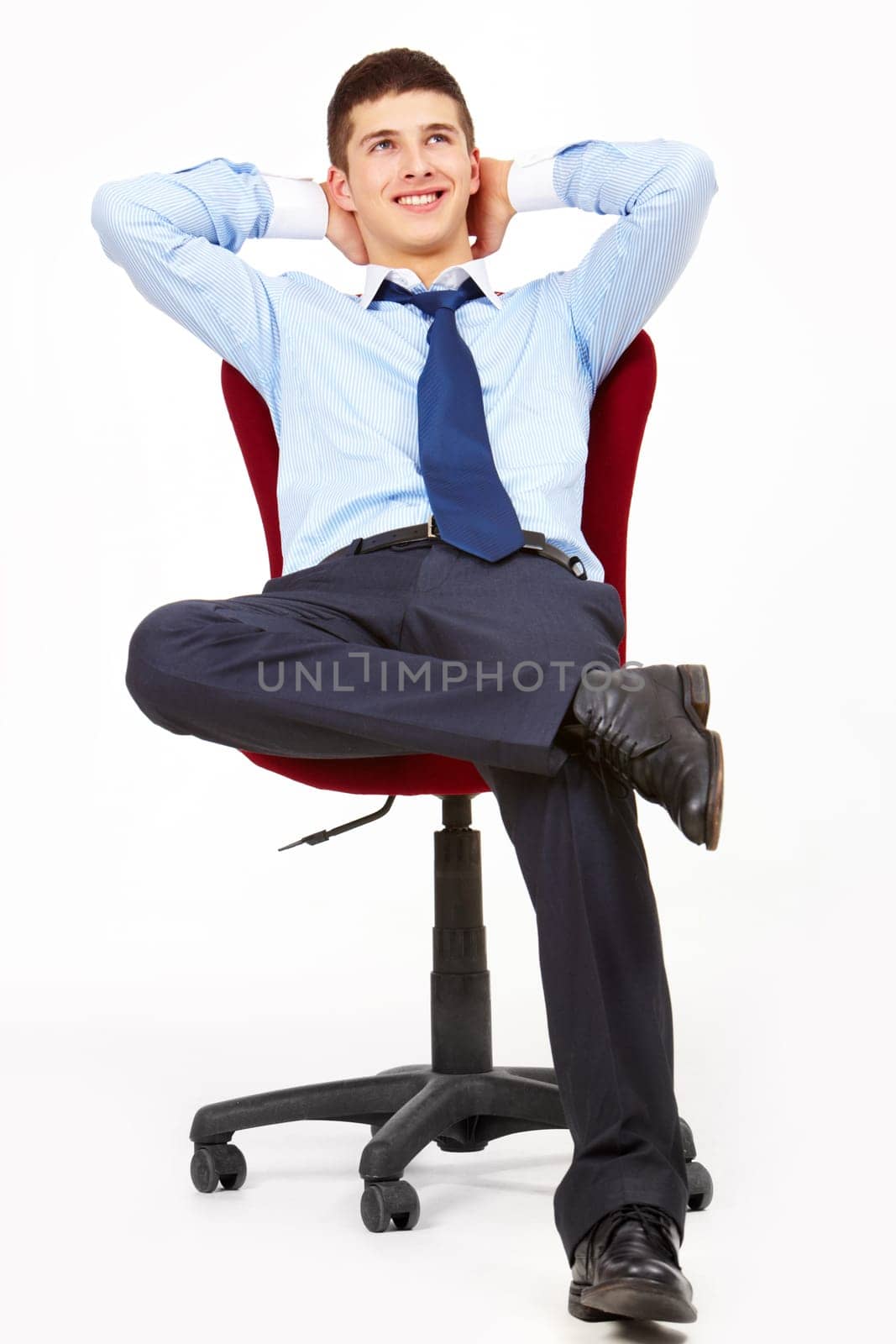 Portrait of positive man relaxing in arm-chair with hands behind head
