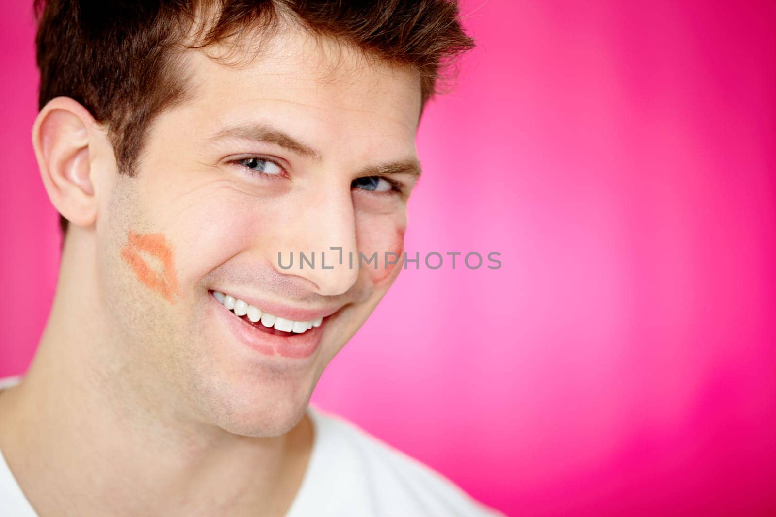 Handsome man with print of lipstick on his cheek smiling at camera