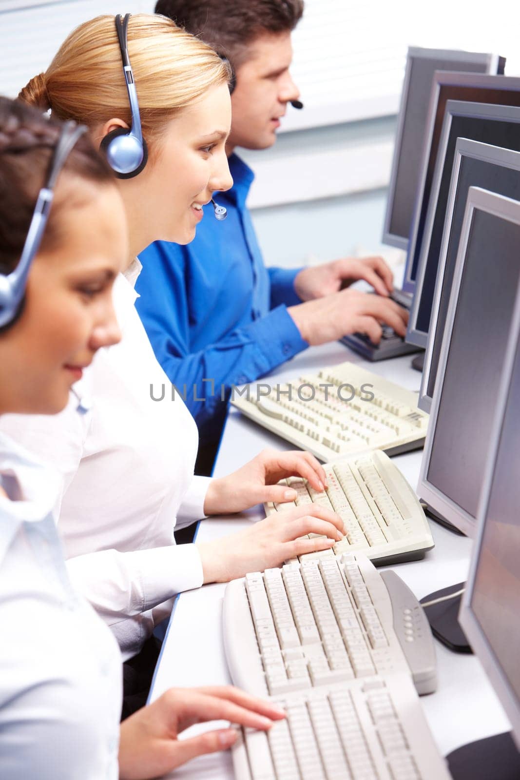 Row of telephone operators looking at the monitors and working