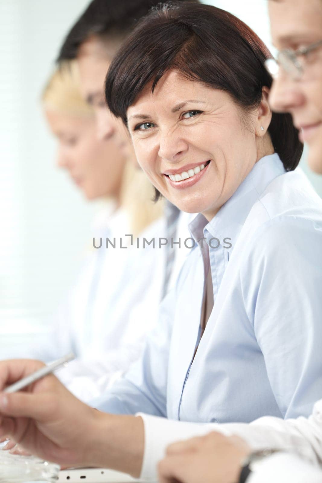 Mature businesswoman looking at camera between her partners