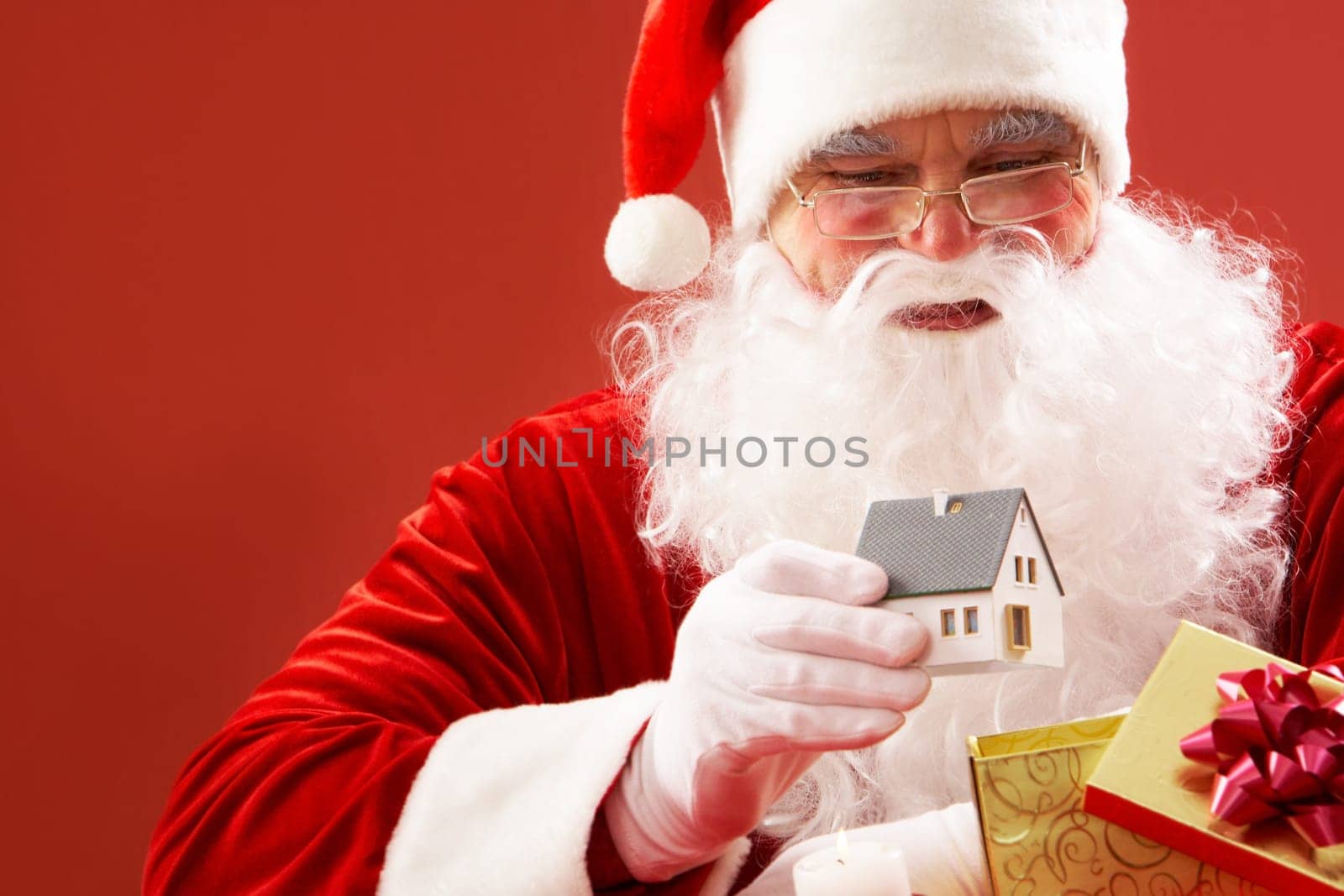 Photo of Santa Claus putting toy house into small giftbox
