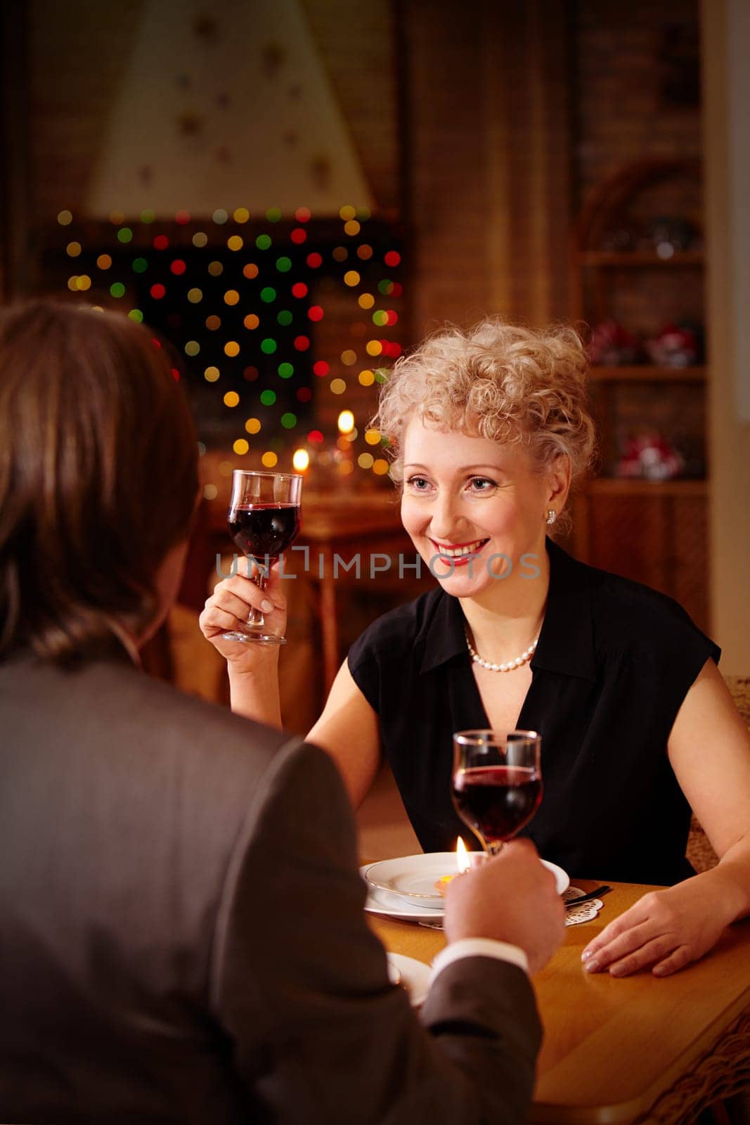 Image of happy female toasting in restaurant while looking at her sweetheart