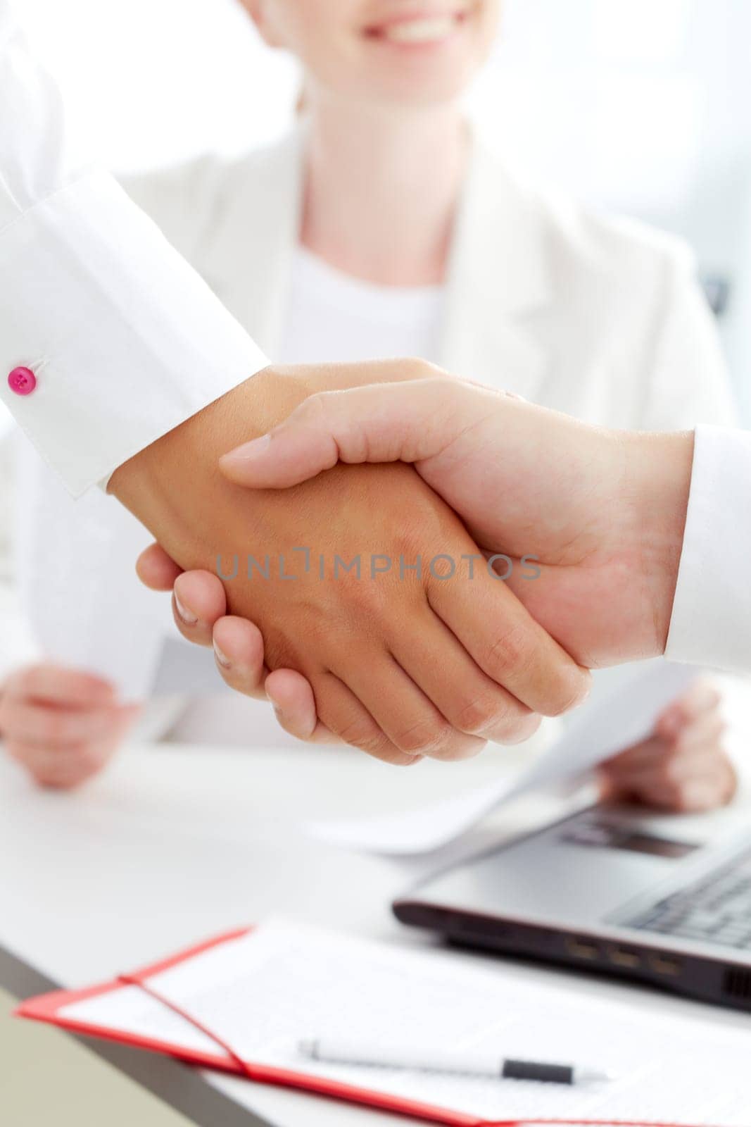 Image of handshaking of business partners with female on background