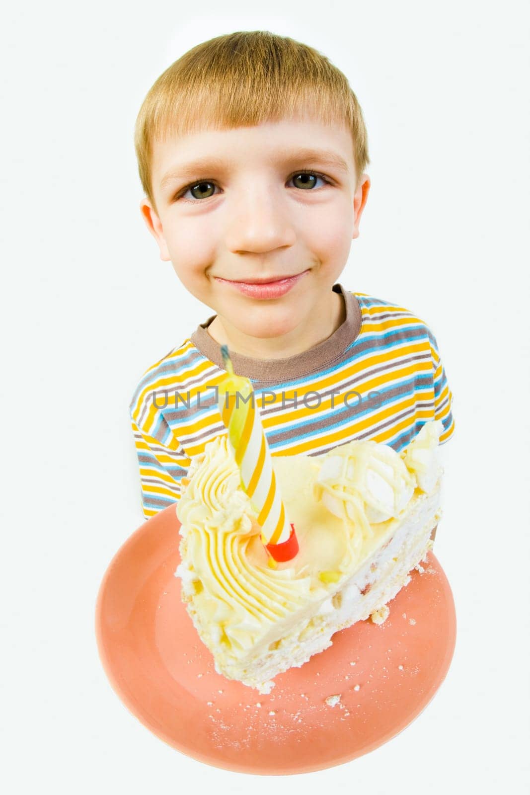 Photo of saucer with a piece of birthday cake on it on the background of cute boys face looking at camera
