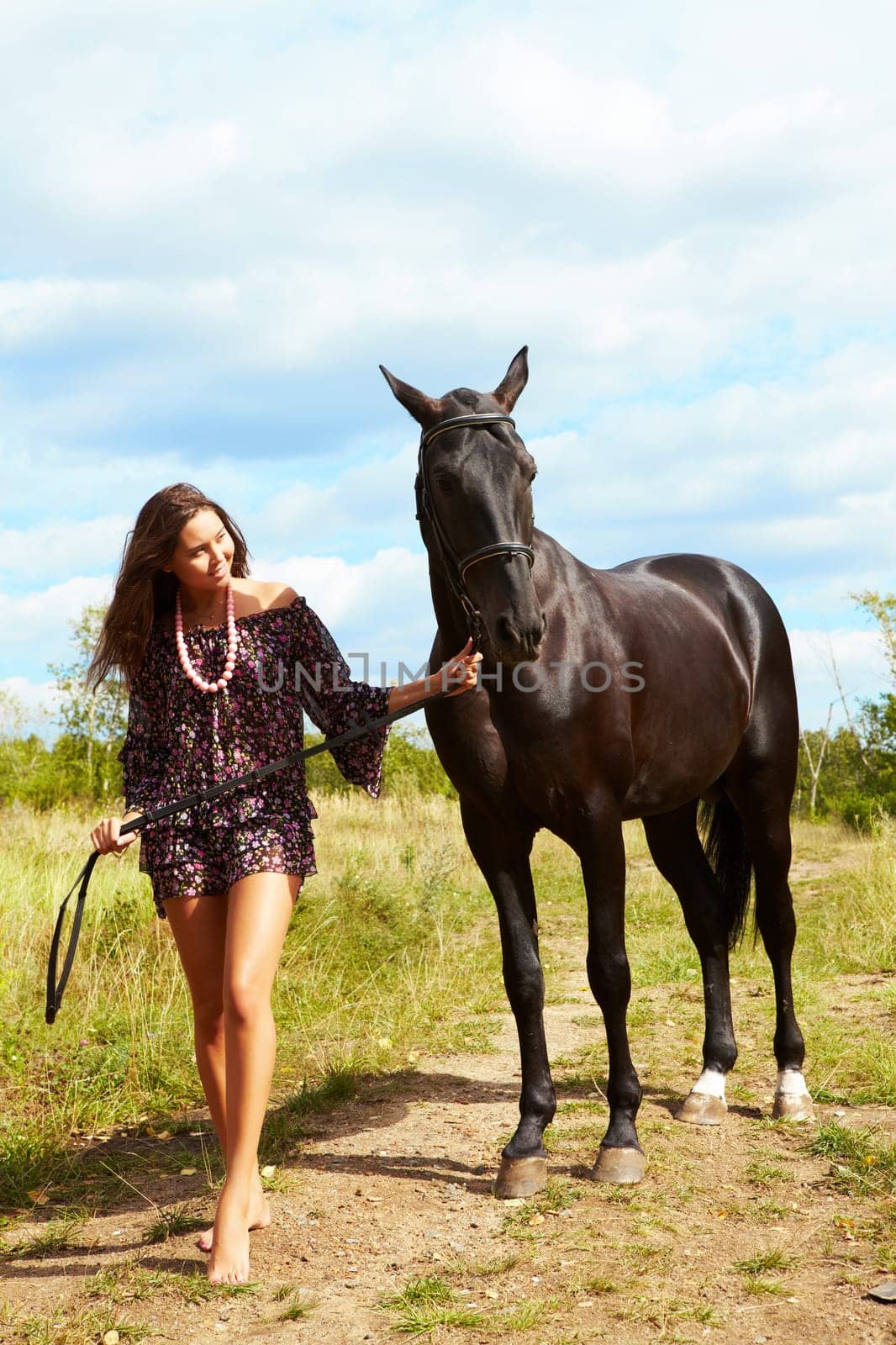 Image of barefoot female walking down path with purebred horse outdoors