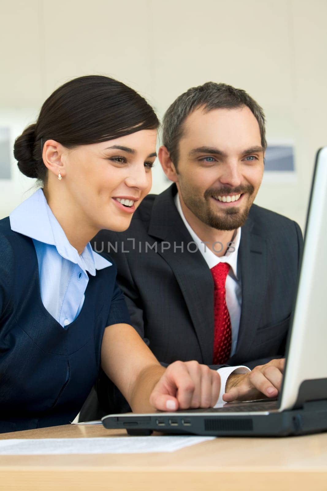 Portrait of happy partners looking at laptop monitor and discussing new project