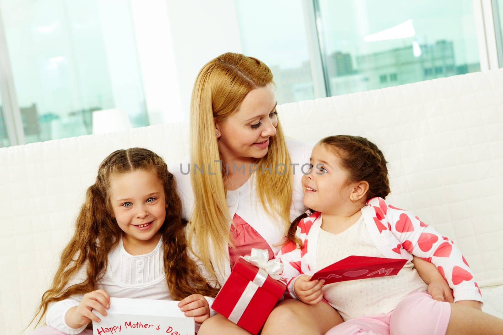 Loving mother with her two pretty daughters interacting at home
