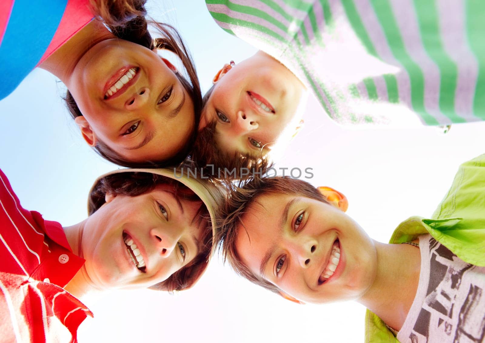 Below view of several happy teens standing head by head to each other