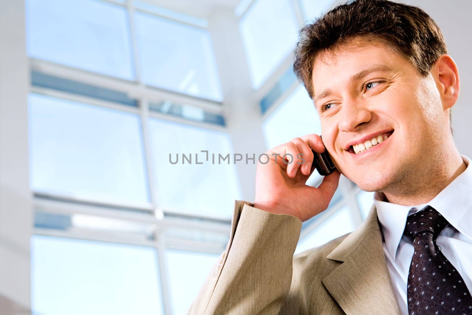 Image of business man calling by phone on the background large window