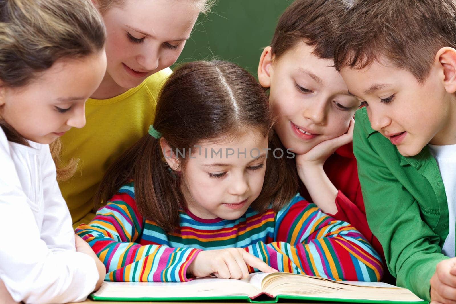 Portrait of friendly group reading book in classroom