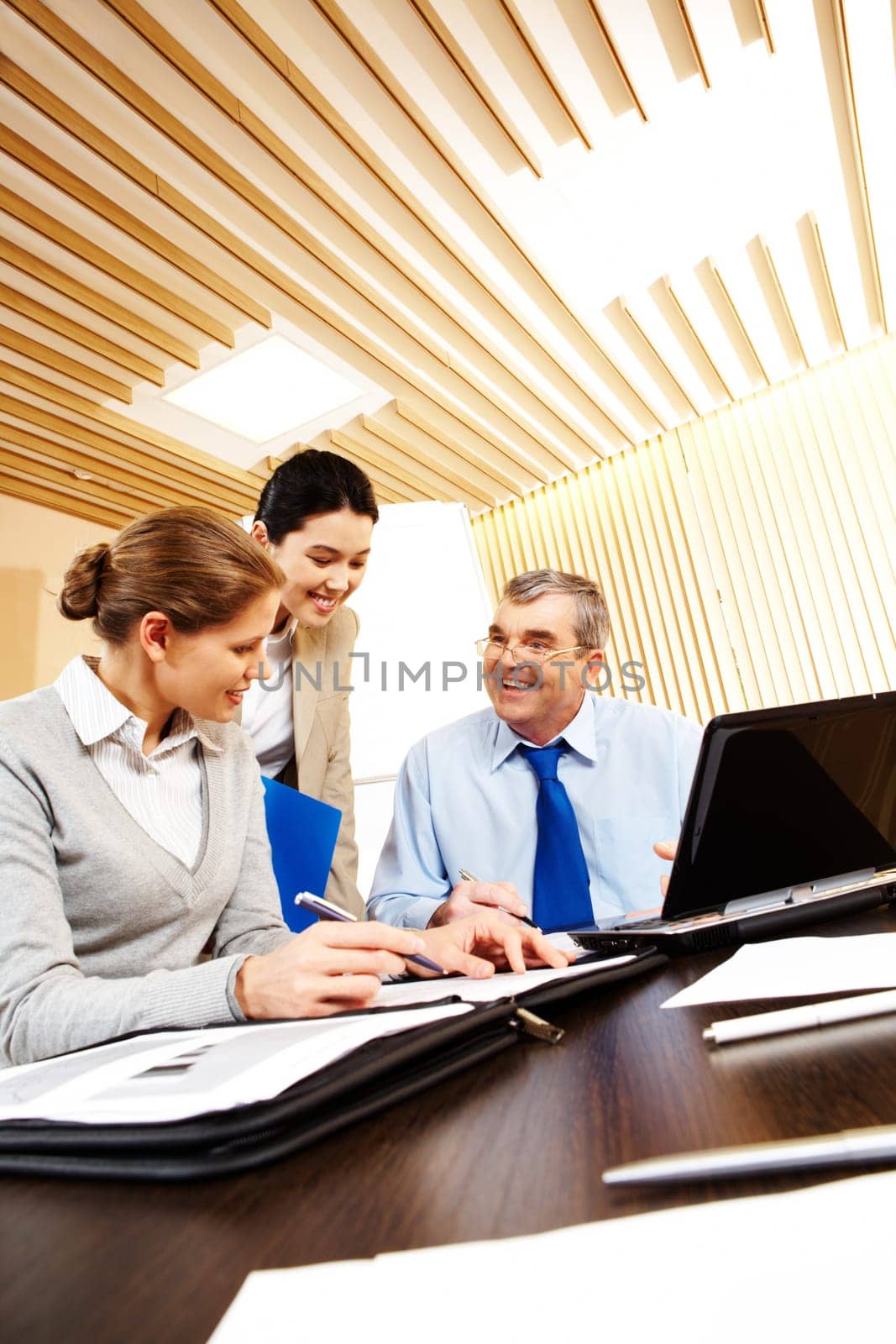 Photo of friendly business group sitting at the desk in the office and planning work