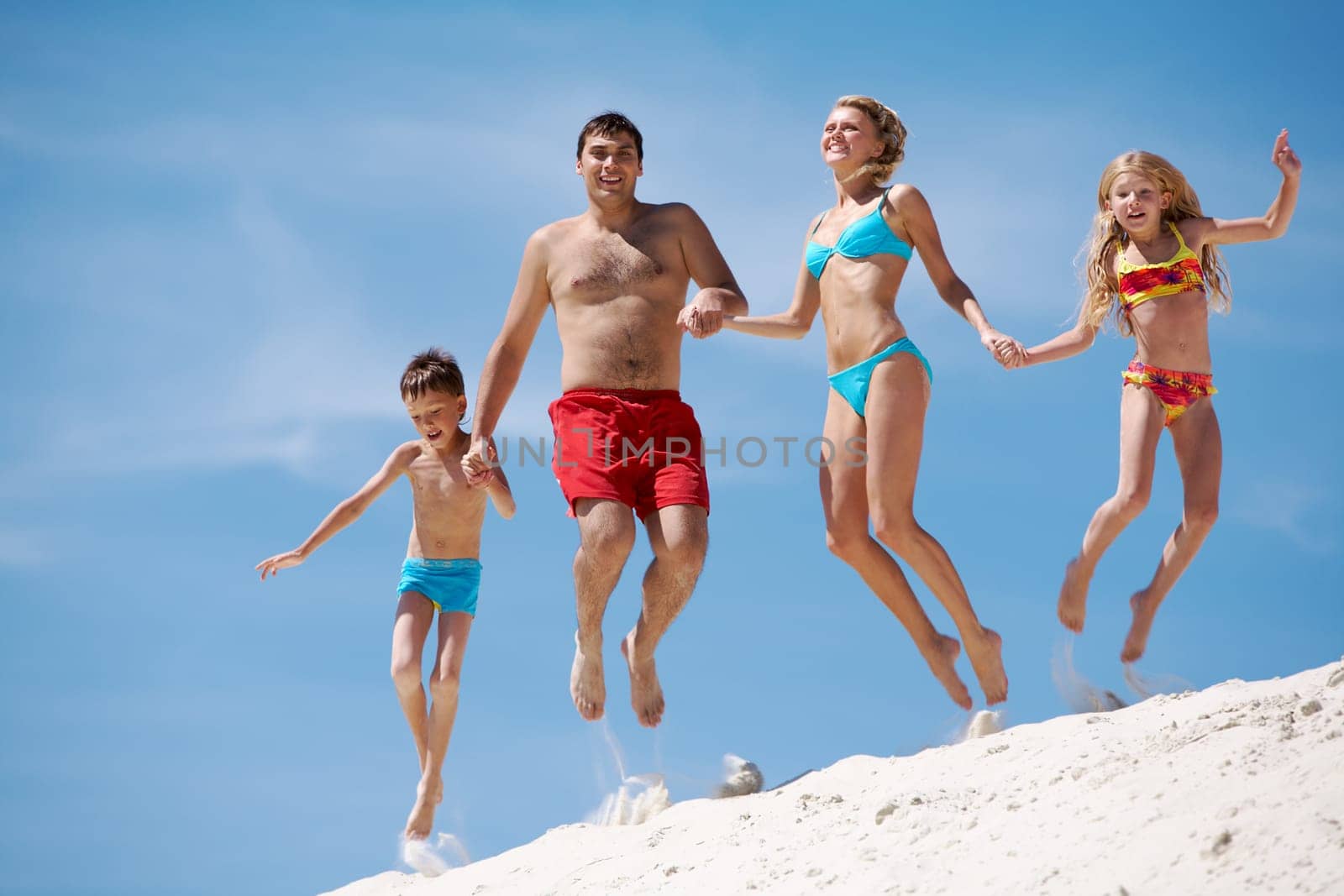 Photo of happy family jumping on sand on summer vacation