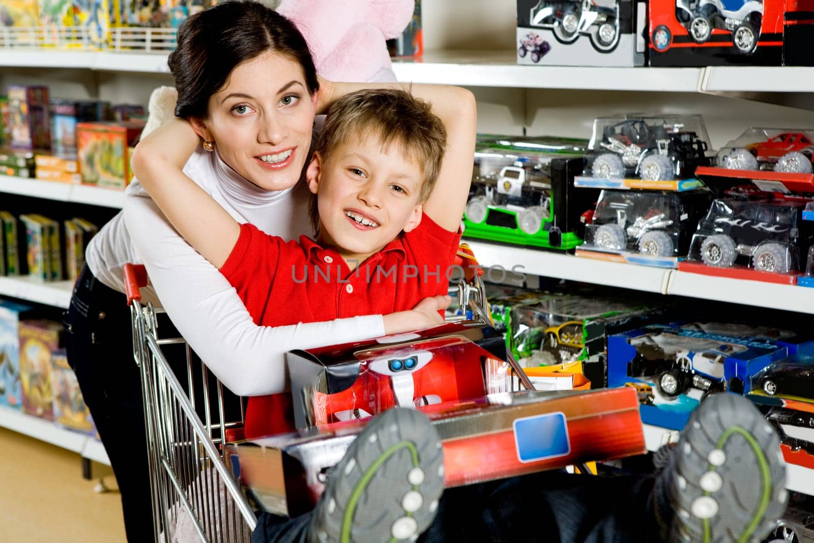 Portrait of pretty woman embracing her son and both looking at camera with smiles