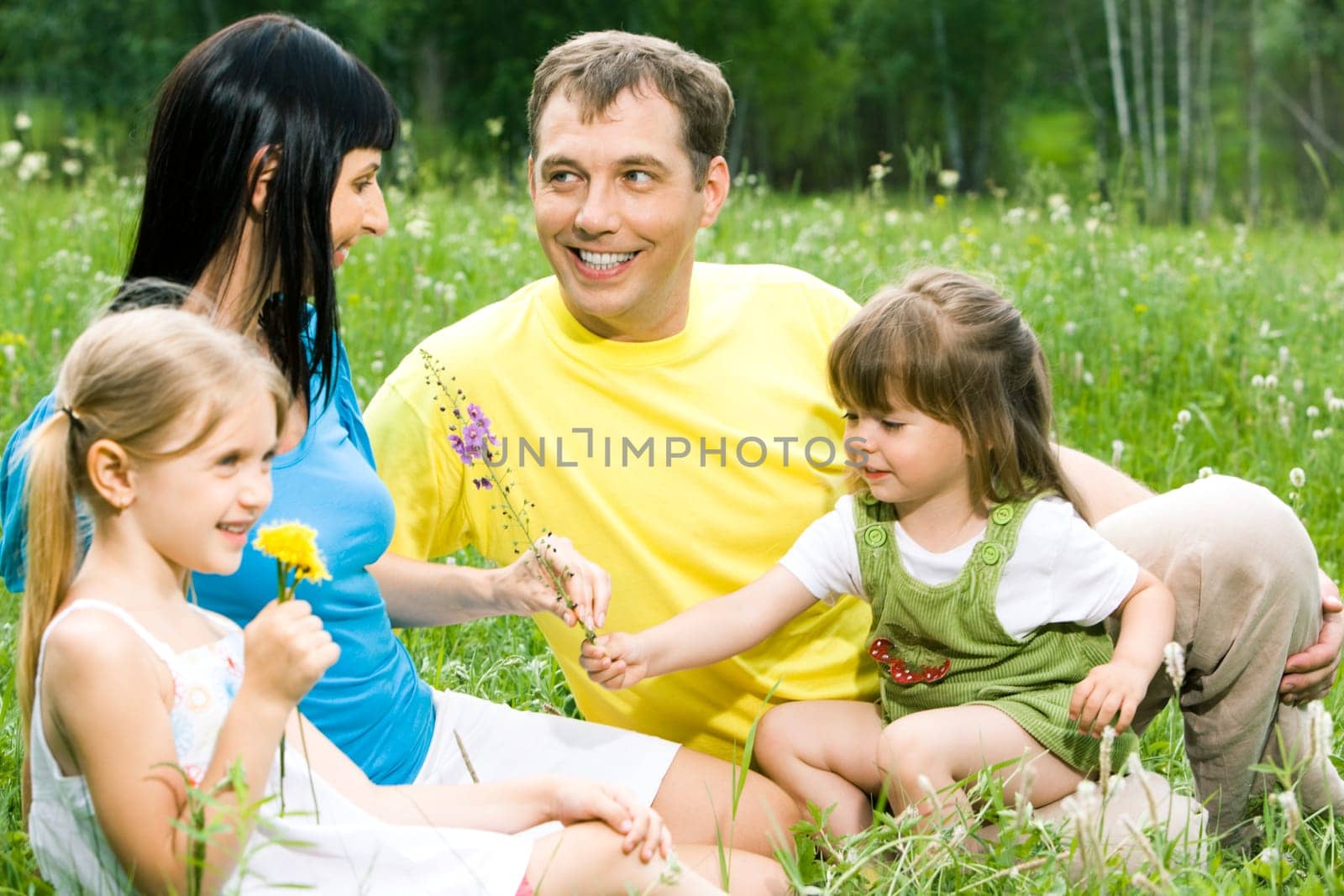 Portrait of little girl giving flower to her mother with father and sister near by