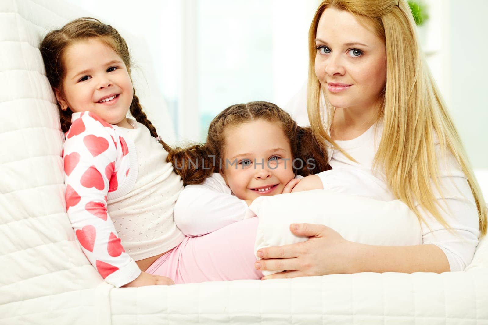 Loving mother with her two pretty daughters having rest at home