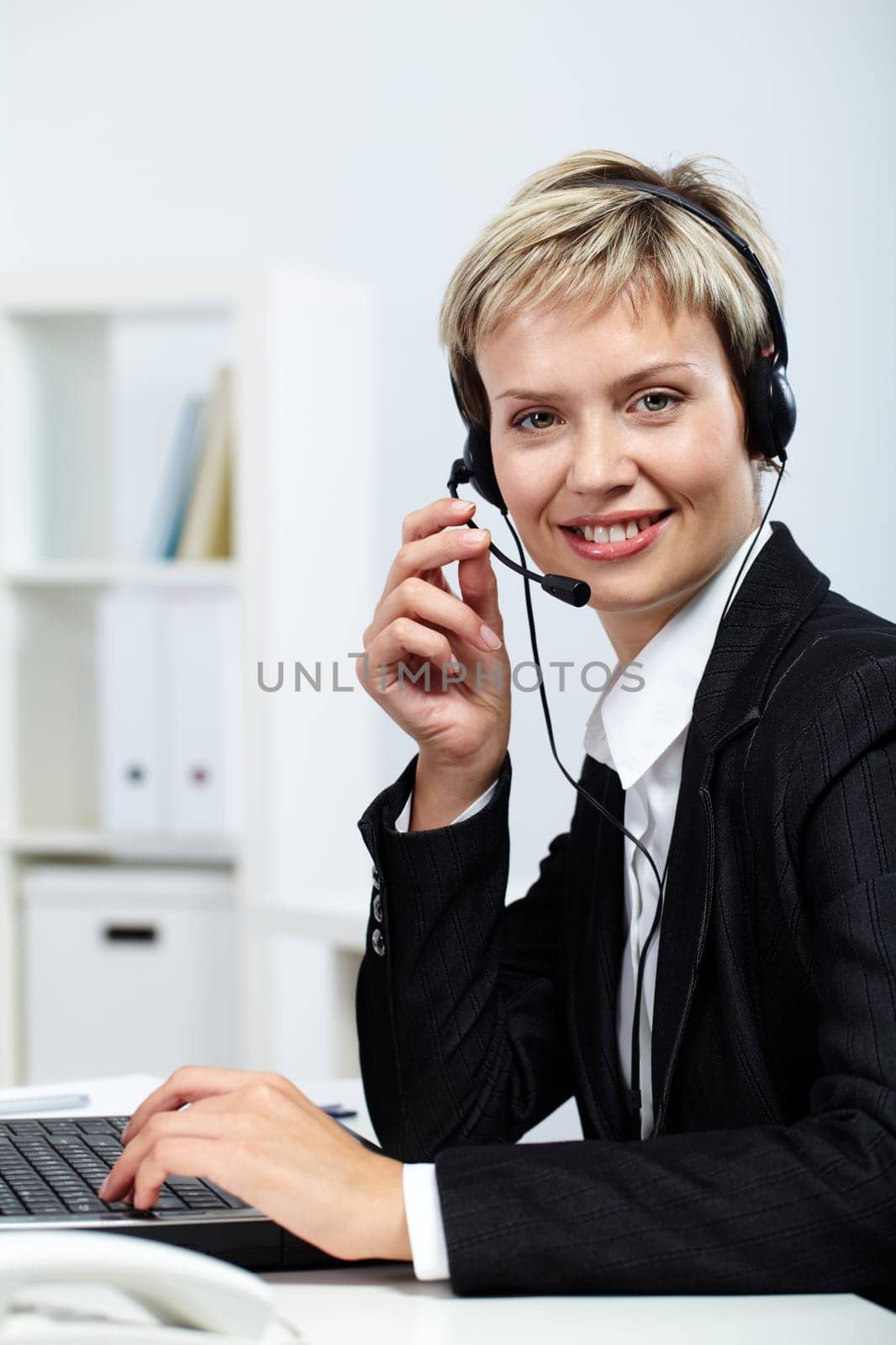 Portrait of pretty secretary answering a call and typing