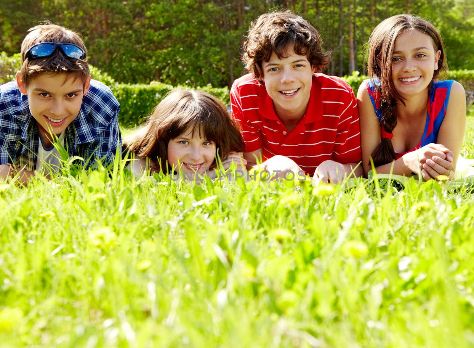 Photo of several happy friends lying on green lawn outdoors