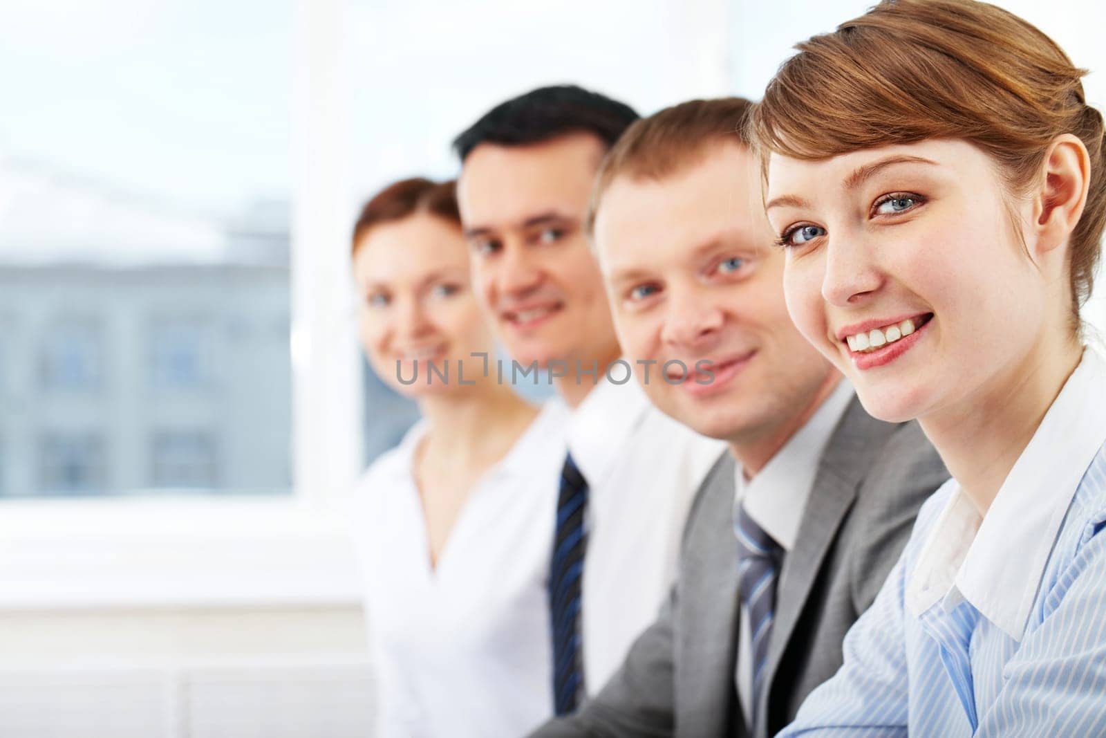 Portrait of friendly leader looking at camera with three employees behind