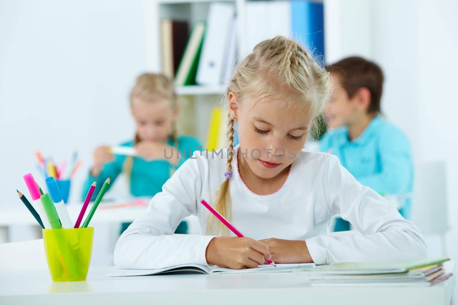 Portrait of lovely girl drawing with classmates on background