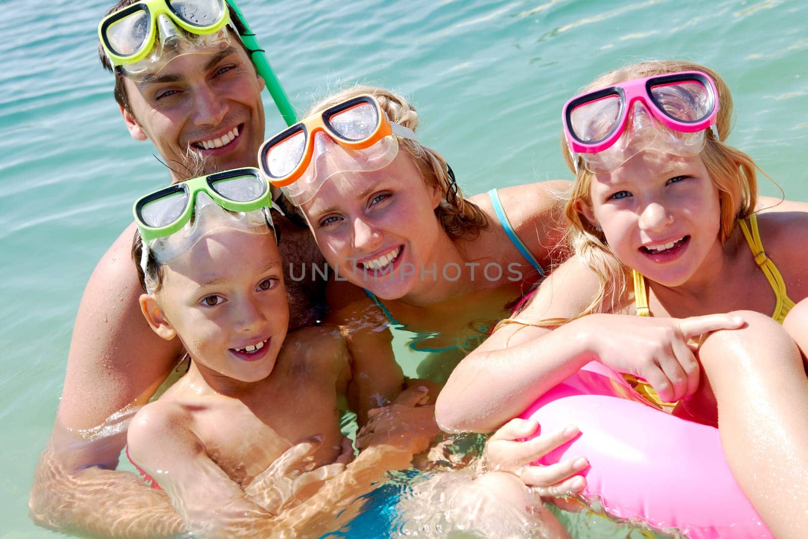 Portrait of cheerful family in aqualungs looking at camera from water