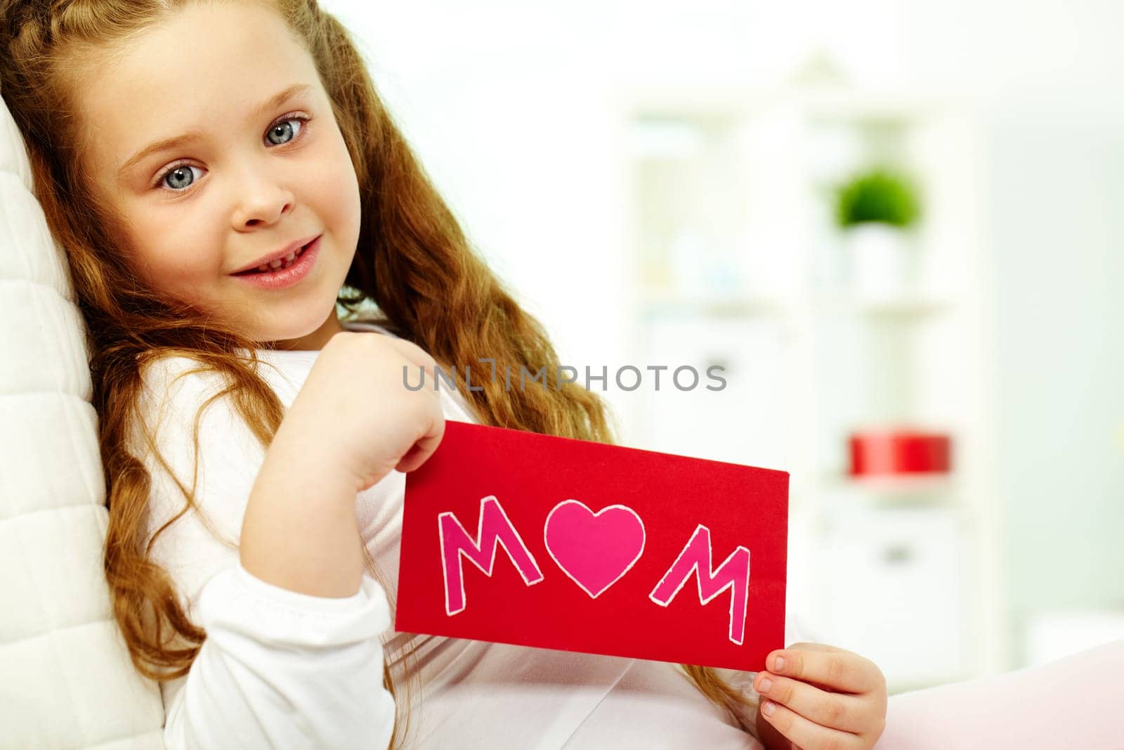 Portrait of happy girl showing envelope with congratulation card and looking at camera
