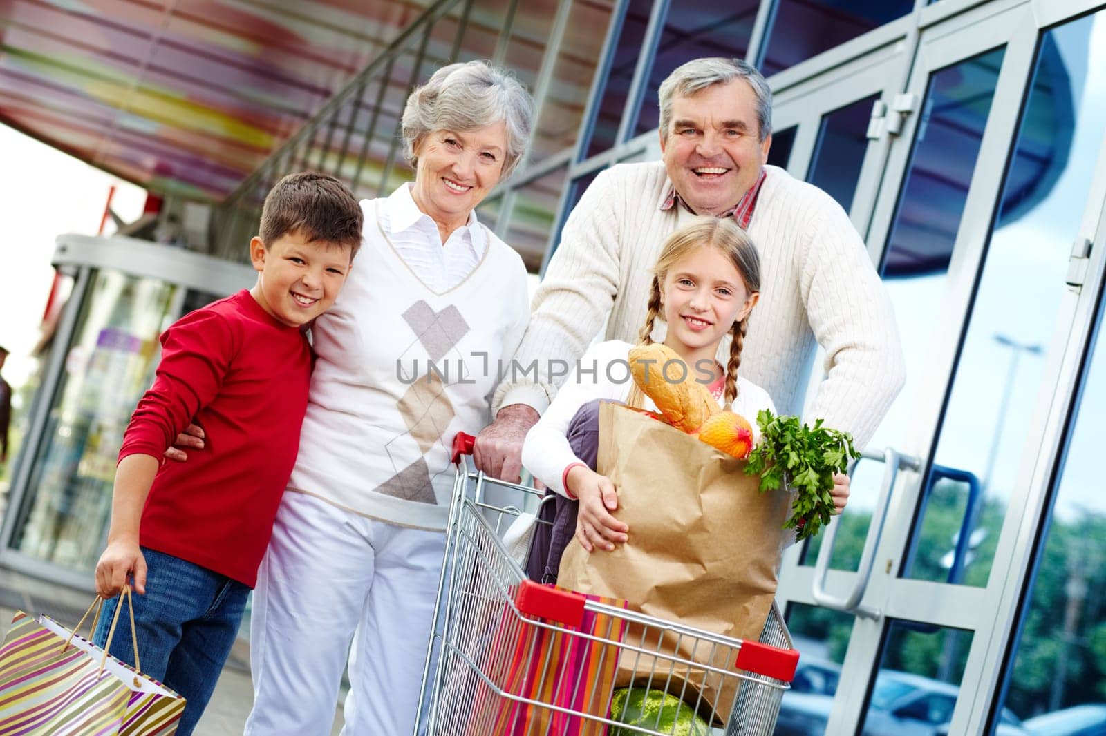 Portrait of happy grandparents and grandchildren near supermarket