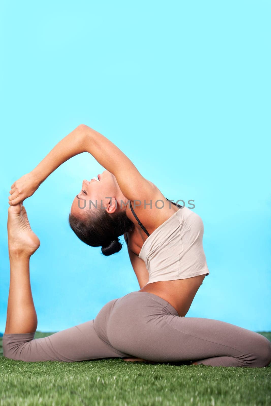 Portrait of happy young woman doing stretching exercise on grass