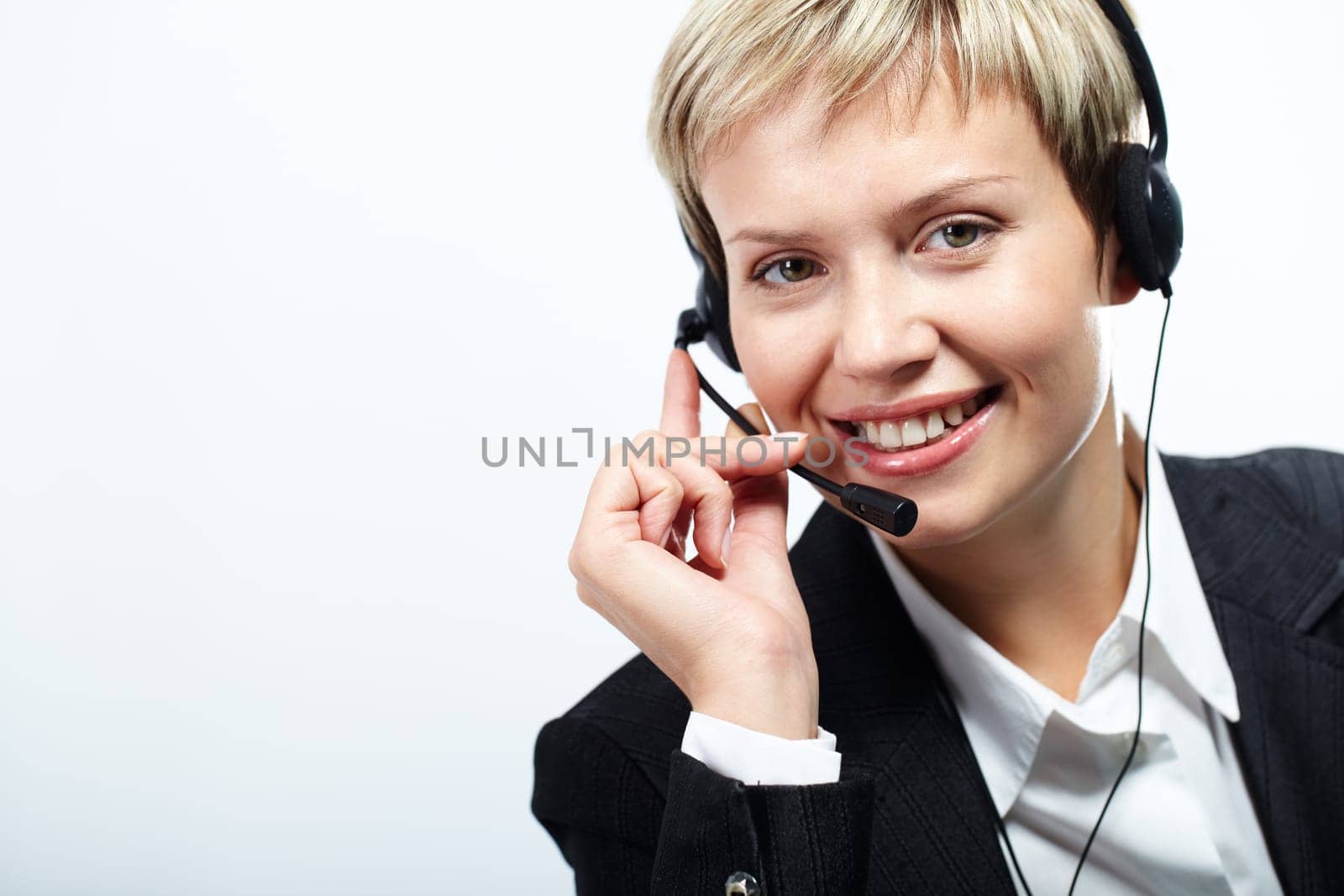 Young pretty operator with headset looking at camera and smiling isolated on white