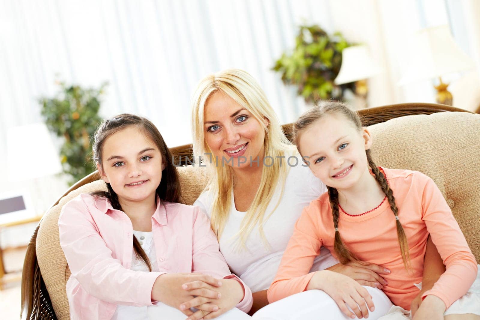 Portrait of happy mother and two daughters sitting on sofa