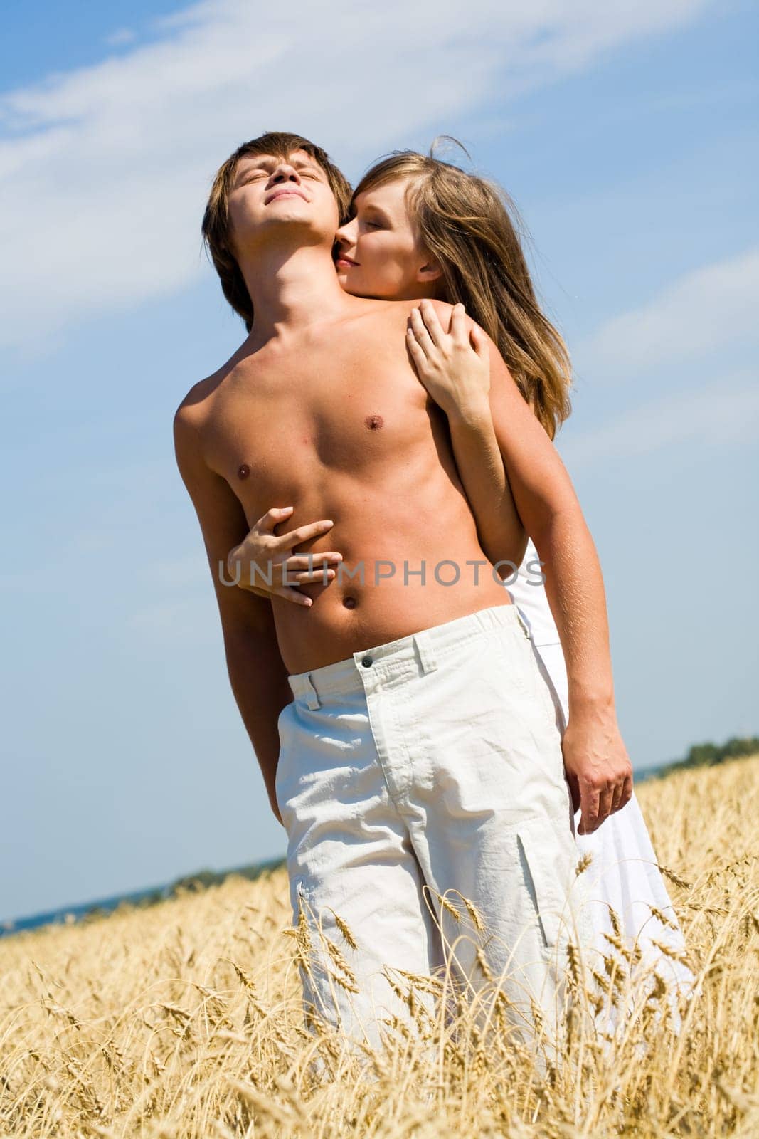 Portrait of handsome male being hugged by his loving girlfriend in the countryside