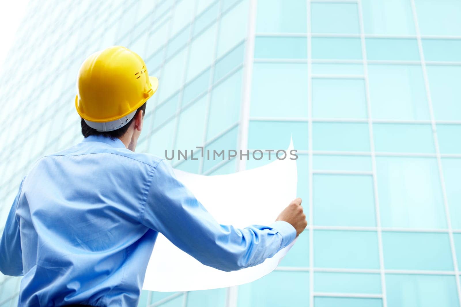Rear view of architect looking comparing housing project with building