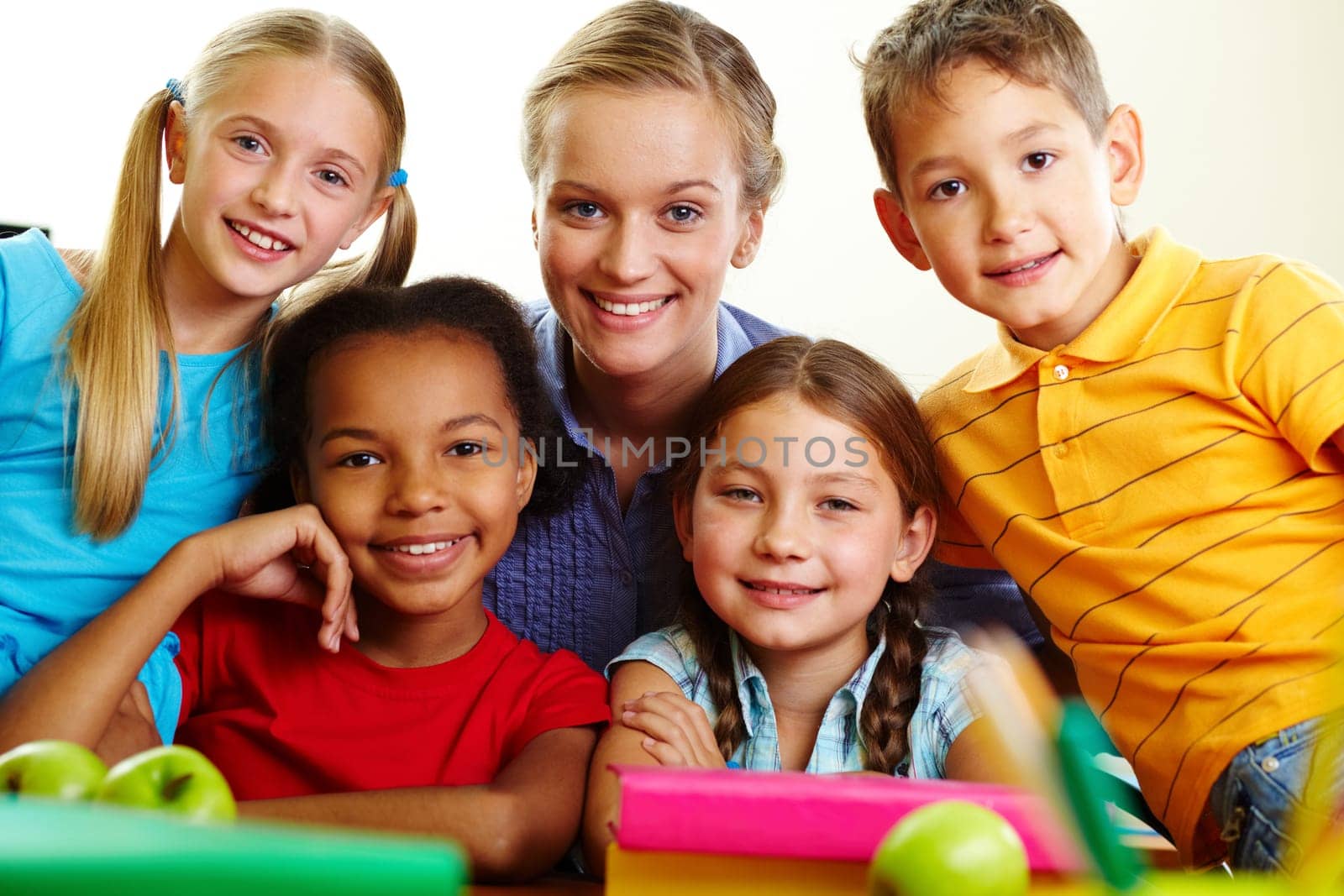 Portrait of smart schoolchildren and their teacher looking at camera in classroom
