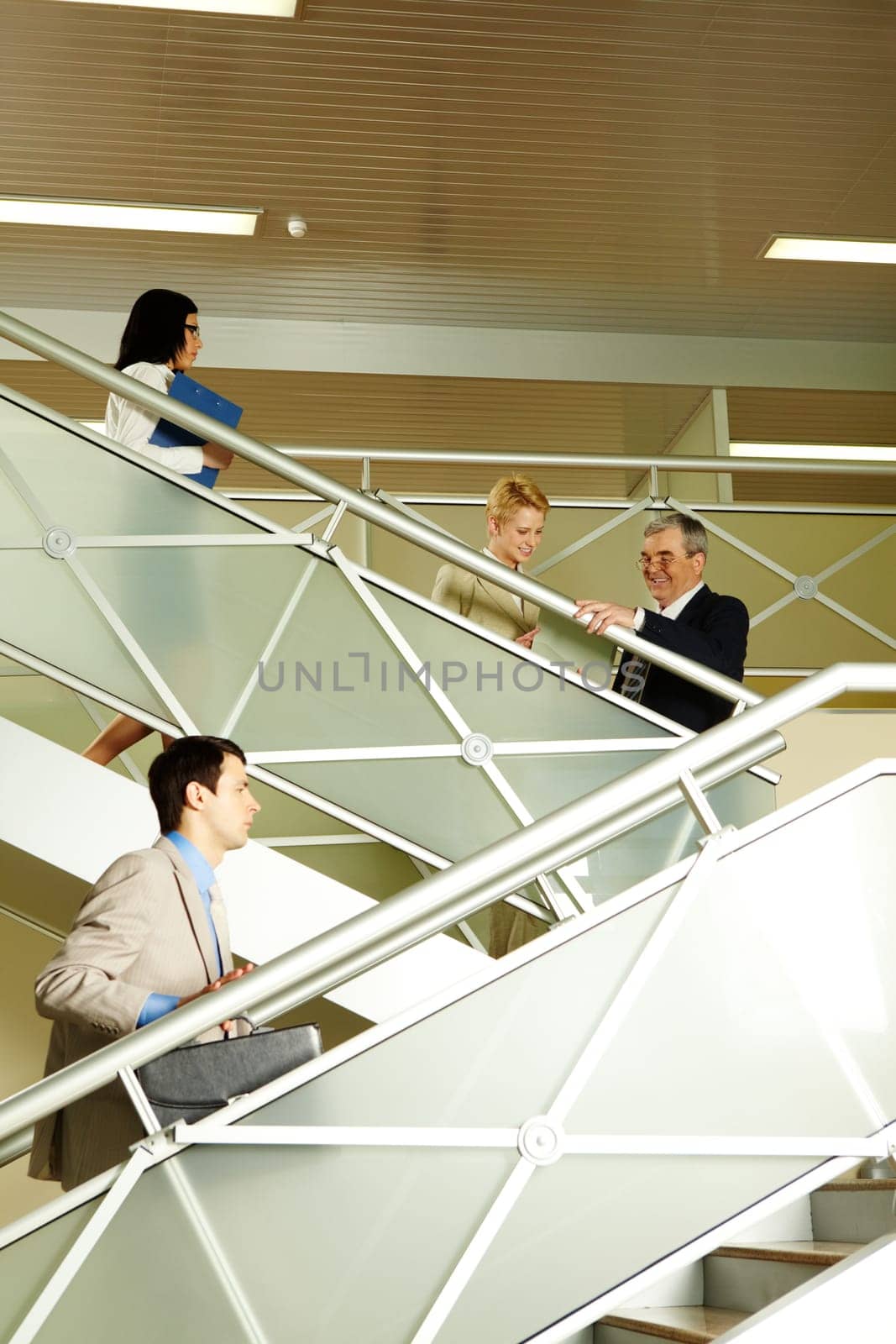 Photo of busy partners communicating while going upstairs in office building