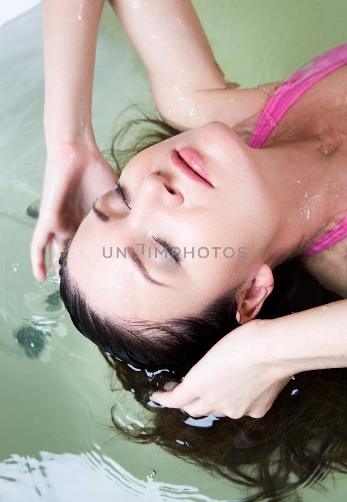 Image of serene woman with closed eyes having pleasant bath with her hair in water